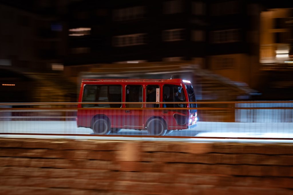 A red bus speeds through the night.
