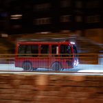 A red bus speeds through the night.
