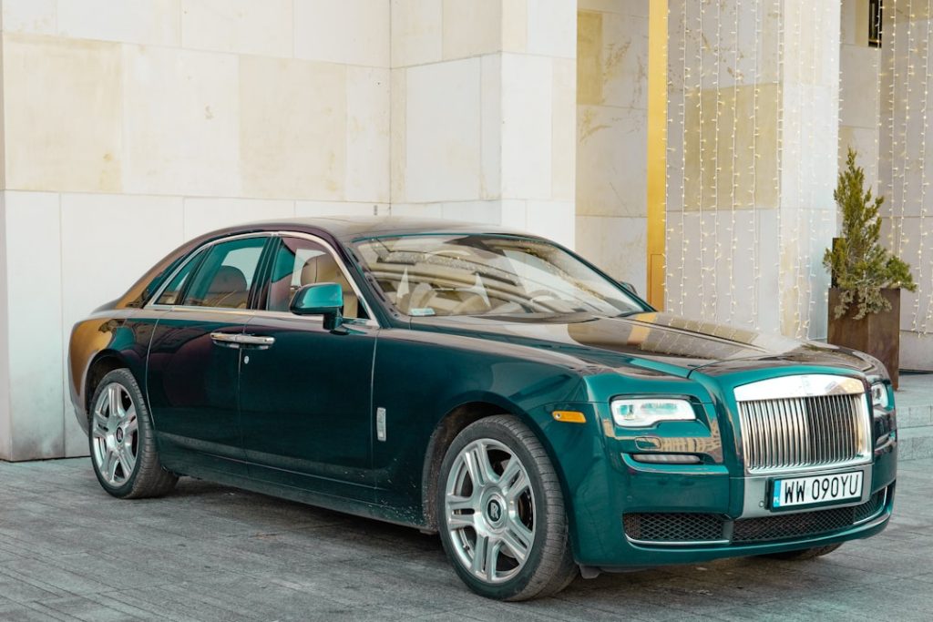 A dark green rolls-royce sedan parked outside.