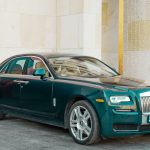 A dark green rolls-royce sedan parked outside.