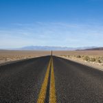 straight asphalt road between desert at daytime