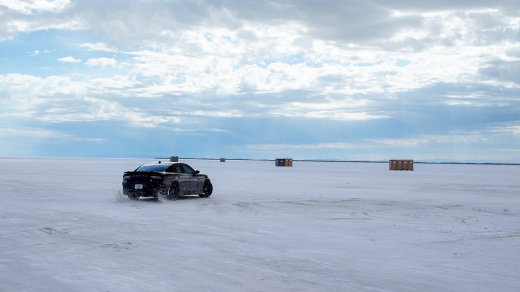 A car is driving through the snow on a cloudy day