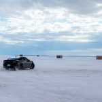 A car is driving through the snow on a cloudy day
