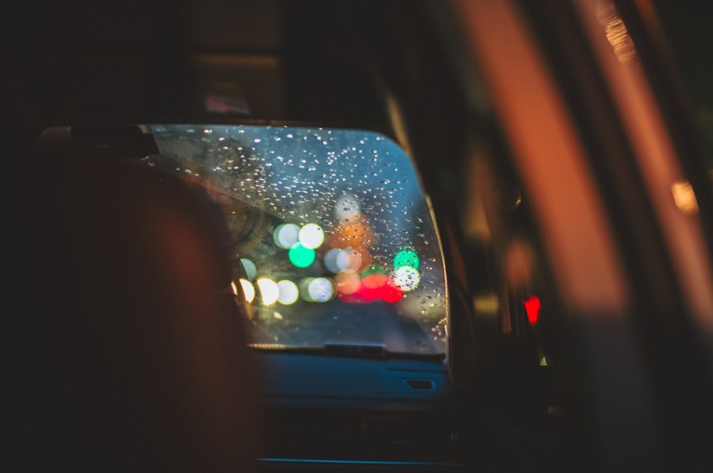 a car's rear view mirror with blurry lights in the background